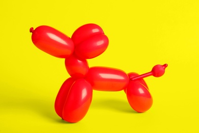 Red dog figure made of modelling balloon on yellow background