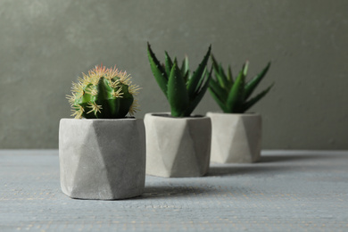 Artificial plants in ceramic flower pots on grey wooden table