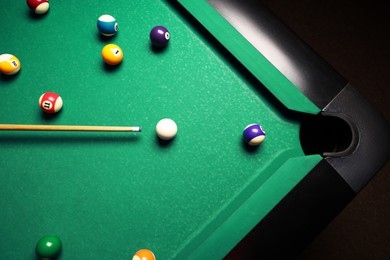 Photo of Many colorful billiard balls and cue on green table, top view