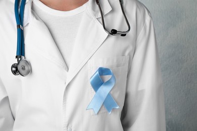 Photo of Doctor with light blue awareness ribbon, closeup