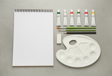 Flat lay composition with blank sketchbook on light grey stone table. Space for text