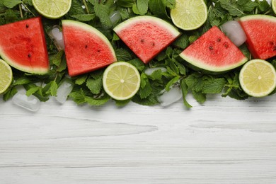Tasty sliced watermelon, limes, mint and ice on white wooden table, flat lay. Space for text
