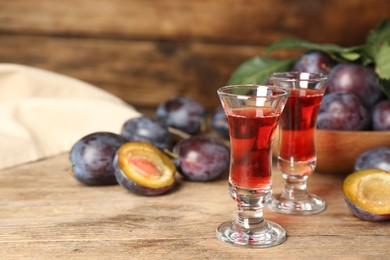 Delicious plum liquor and ripe fruits on wooden table. Homemade strong alcoholic beverage