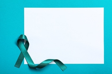 Teal ribbon and blank card on color background, top view. Space for text