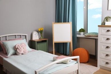 Stylish child room interior with comfortable bed and board