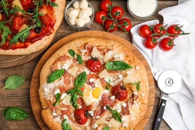 Delicious pita pizzas with prosciutto, pineapple, grilled tomatoes and egg on wooden table, flat lay