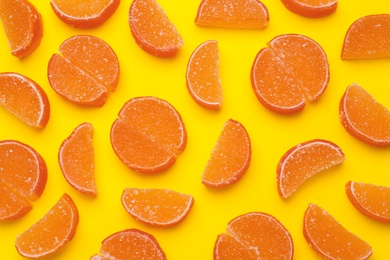 Delicious orange marmalade candies on yellow background, flat lay