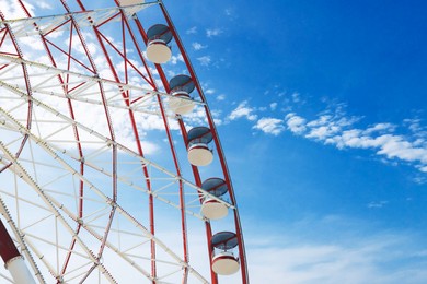 Beautiful large Ferris wheel against blue sky with clouds on sunny day