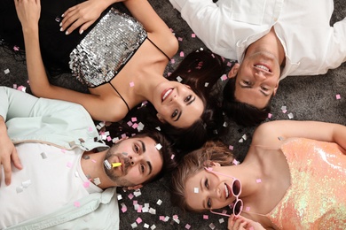 Group of friends lying on messy floor after party, top view