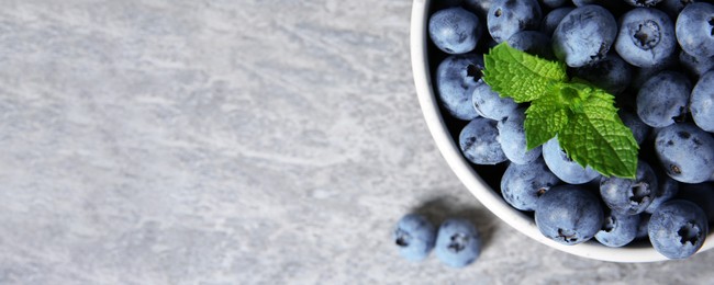 Tasty fresh blueberries on grey table, top view with space for text. Banner design