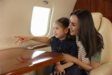 Mother with daughter looking out window in airplane during flight