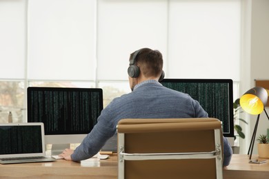 Programmer with headphones working at desk in office