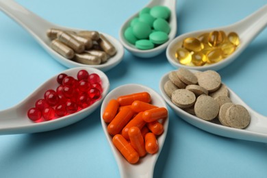 Photo of Spoons with different dietary supplements on light blue background, closeup