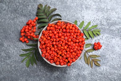 Fresh ripe rowan berries and leaves on grey table, flat lay