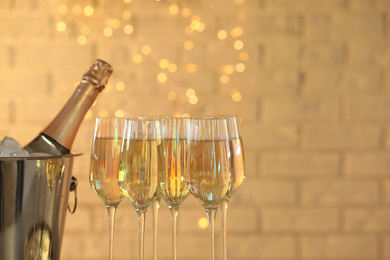 Glasses of champagne and ice bucket with bottle on blurred background