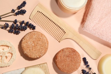 Flat lay composition of solid shampoo bars, lavender and comb on pink background. Hair care