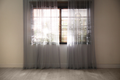 Window with beautiful curtains and blinds in empty room