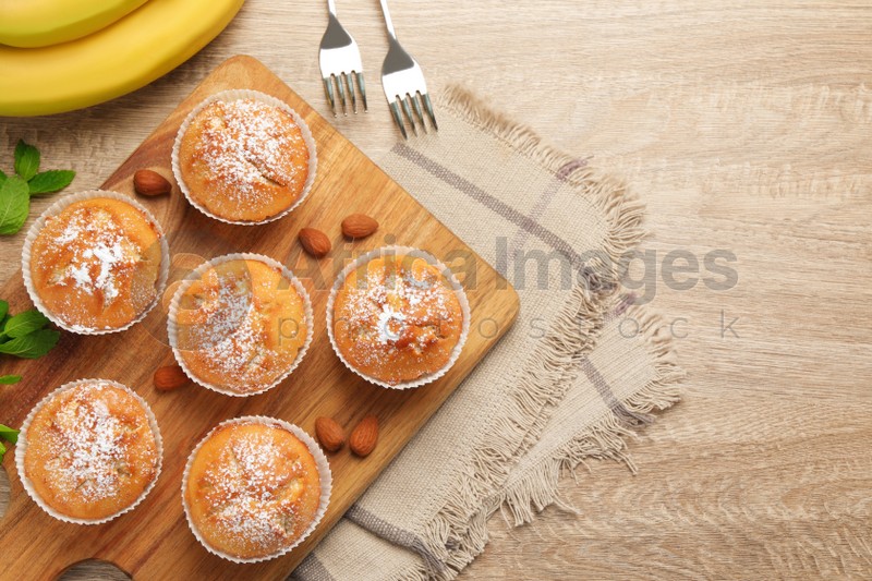 Photo of Flat lay composition with tasty banana muffins on wooden table. Space for text