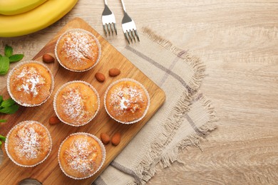 Flat lay composition with tasty banana muffins on wooden table. Space for text