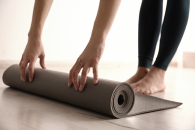 Young woman with yoga mat indoors, closeup