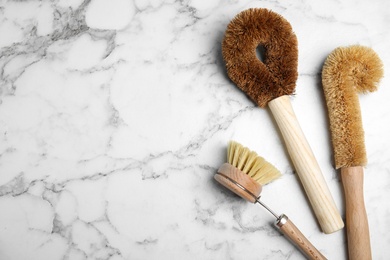 Cleaning brushes on white marble table, flat lay with space for text. Dish washing supplies