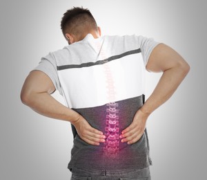 Man having backache on light background. Digital compositing with illustration of spine 