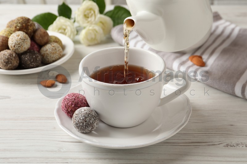 Pouring tea into cup on white wooden table