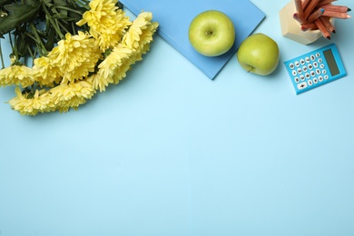 Flat lay composition with flowers, stationery and apples on light blue background, space for text. Teacher's day