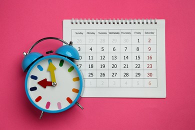Alarm clock and calendar on pink background, flat lay. Reminder concept