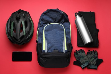 Flat lay composition with different cycling accessories and clothes on red background