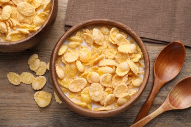 Tasty cornflakes with milk in bowls on wooden table, flat lay