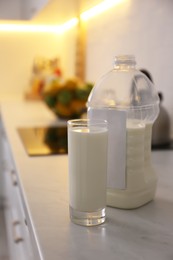 Gallon bottle of milk and glass on white countertop in kitchen