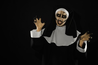 Scary devilish nun frightening on black background, space for text. Halloween party look