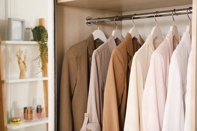 New stylish clothes hanging in wardrobe, closeup view