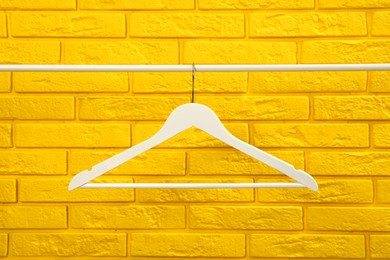 Photo of Wardrobe rack with white hanger near yellow brick wall