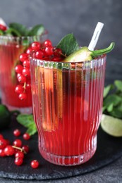 Photo of Glasses of spicy red currant cocktail with jalapeno and mint on grey table, closeup