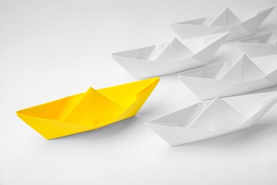 Photo of Group of paper boats following yellow one on white background. Leadership concept