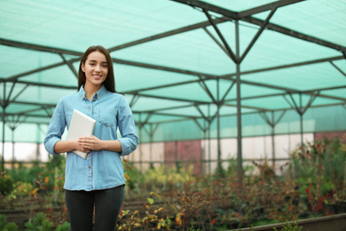 Photo of Female business owner with tablet in greenhouse. Space for text