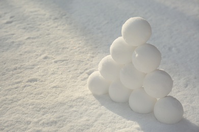 Photo of Pyramid of perfect snowballs on snow outdoors. Space for text