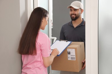 Woman signing for delivered parcel at home