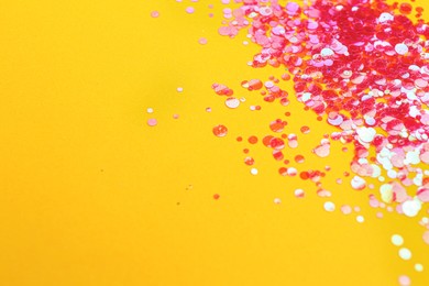 Photo of Shiny bright pink glitter on yellow background. Space for text