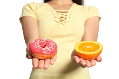 Photo of Concept of choice. Woman holding orange and doughnut on white background, closeup
