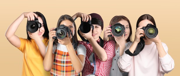 Group of professional photographers with cameras on beige background. Banner design