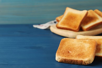 Slices of tasty toasted bread on blue wooden table. Space for text