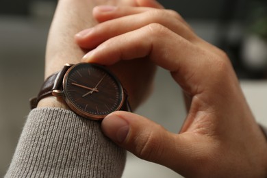 Man with luxury wrist watch on blurred background, closeup