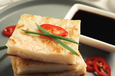 Delicious turnip cake with chili pepper and green onion on plate, closeup