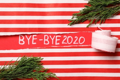Photo of Thuja branches and text Bye-bye 2020 on red background, view through torn striped paper