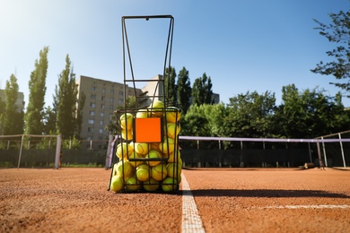 Basket with tennis balls on clay court
