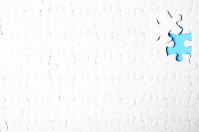 Blank white puzzle with separated piece on light blue background, top view. Space for text