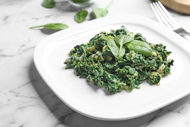 Tasty cooked spinach with scrambled eggs on white marble table, closeup. Healthy food